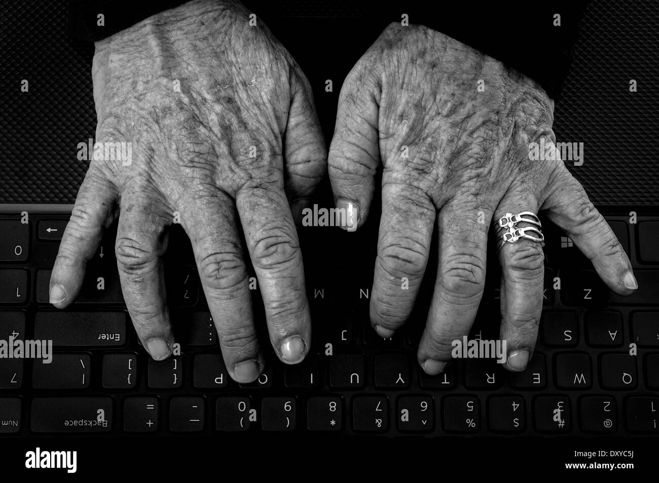 Primo piano della vecchia donna con le mani Artrite su una tastiera di computer in bianco e nero Foto Stock