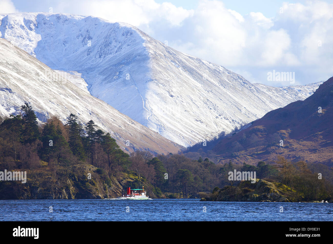 I turisti prendendo un viaggio su un battello a vapore (barca) un lago, con neve sulle colline coperte in background. Ullswater, Lake District, Cumbria. Foto Stock