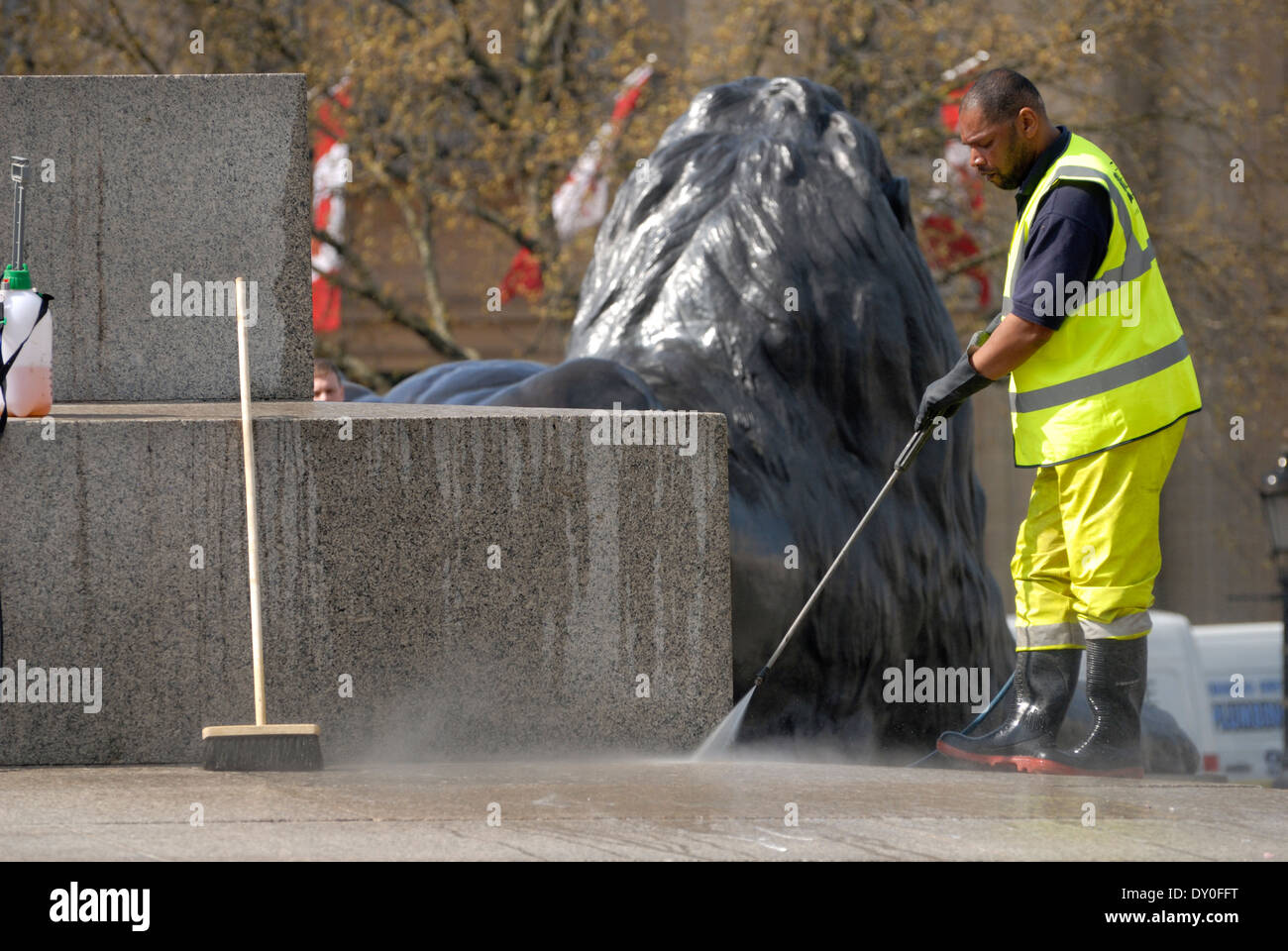 Londra, Inghilterra, Regno Unito. Lavoratore in hi-vis jacket pulitura della base della colonna di Nelson, con un tubo flessibile di alimentazione Foto Stock