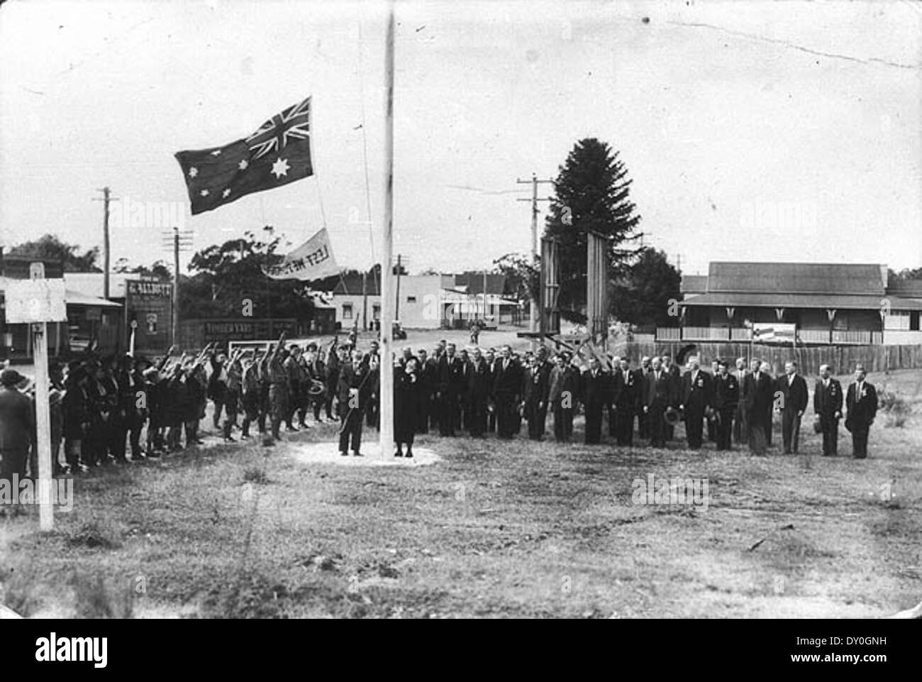 Questa fotografia del 1937 cattura la signora Charles Sharp che sfocia la bandiera nazionale australiana nel giorno ANZAC a Coffs Harbour, nel nuovo Galles del Sud. L'immagine evidenzia il significato del giorno e il rispetto mostrato per coloro che hanno servito nelle forze militari australiane durante la prima guerra mondiale Foto Stock