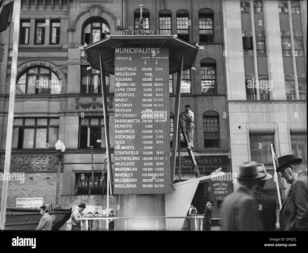 Questa fotografia di Sam Hood, scattata intorno al 1943, mostra il Consiglio dei prestiti a Martin Place, Sydney. L'immagine cattura un momento significativo durante la seconda guerra mondiale, riflettendo l'economia in tempo di guerra e le decisioni finanziarie prese in Australia all'epoca. Foto Stock