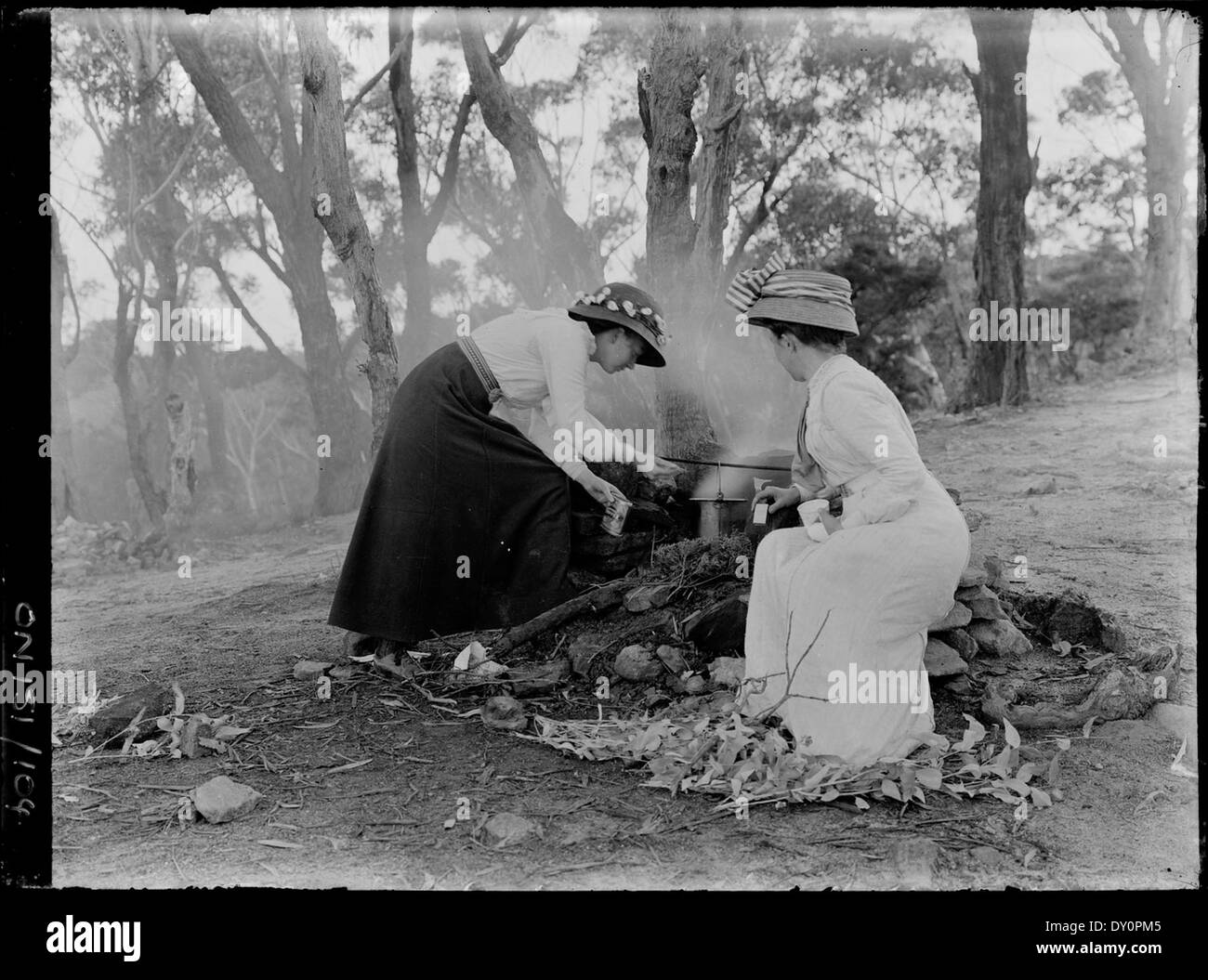 Questa foto di Rex Hazlewood mostra due donne che cucinano sopra un fuoco nel Bush australiano. Scattata tra il 1909 e il 1929, l'immagine cattura la vita quotidiana e le tradizioni all'aperto dell'Australia rurale dei primi anni del XX secolo. Foto Stock