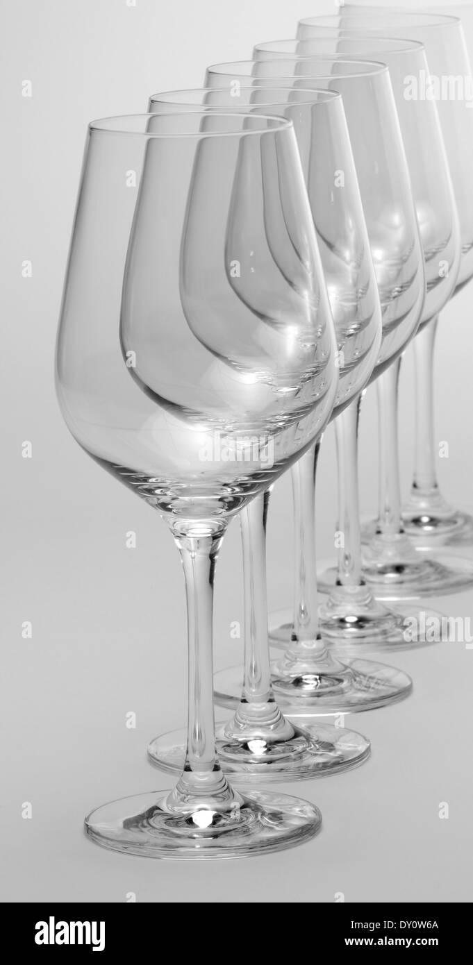 Alcuni vuoti e puliti bicchieri di vino in piedi in una fila in grigio chiaro indietro Foto Stock