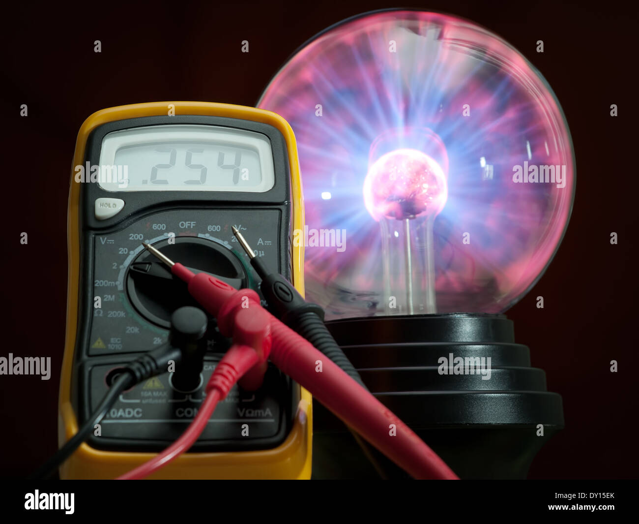 Multimetro digitale e ad alta tensione della lampada plasma in background. Foto Stock