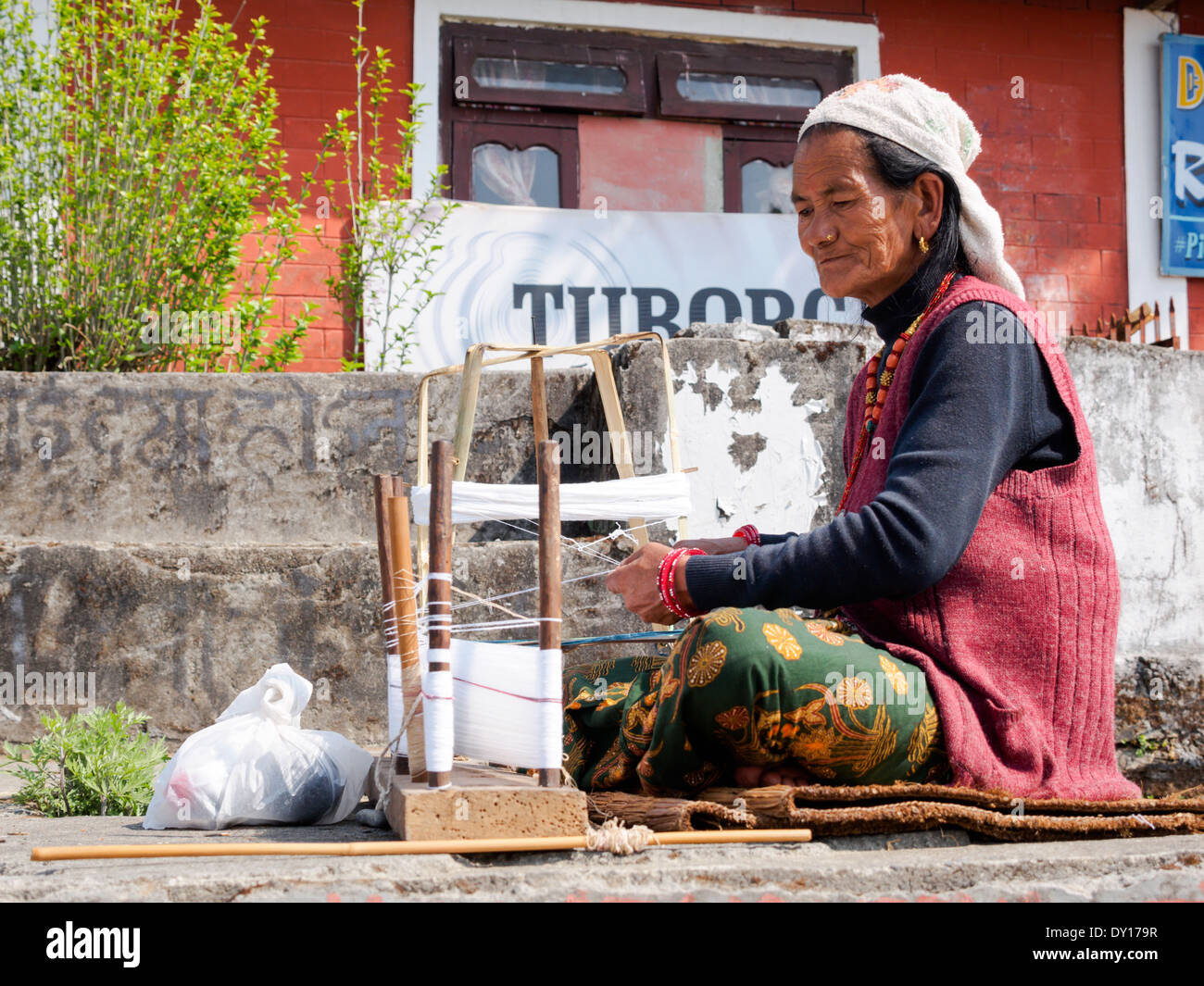Anziana donna Gurung tessitura di una sciarpa tradizionale nel villaggio di Dhampus, Nepal Foto Stock