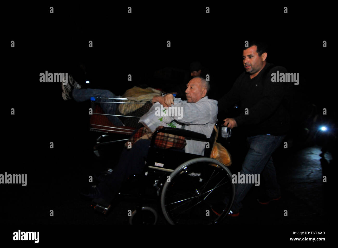 Iquique, Cile. 3 apr, 2014. Un uomo aiuta un anziano su una sedia a rotelle dopo un terremoto, in Iquique, il 3 aprile 2014. Un 7.8-terremoto di magnitudine scossi mare al largo della costa del nord del Cile a 10:43 a.m. Giovedì (ora di Pechino), secondo il terremoto in Cina Centro reti. Credito: AGENCIA ONU/Xinhua/Alamy Live News Foto Stock