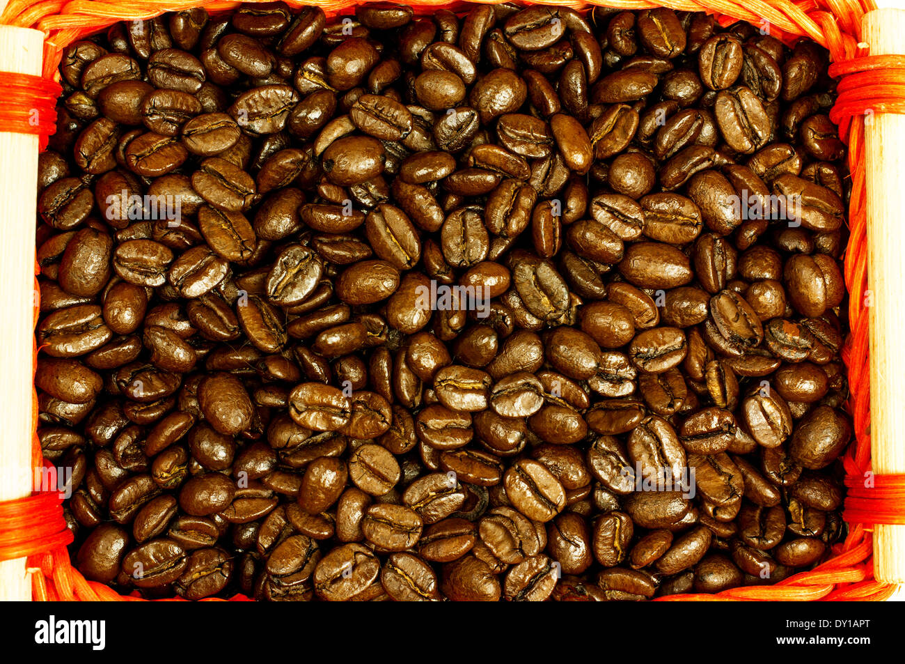 Freschi chicchi di caffè tostati close-up di un rosso cesto in vimini con manici in legno. Foto Stock