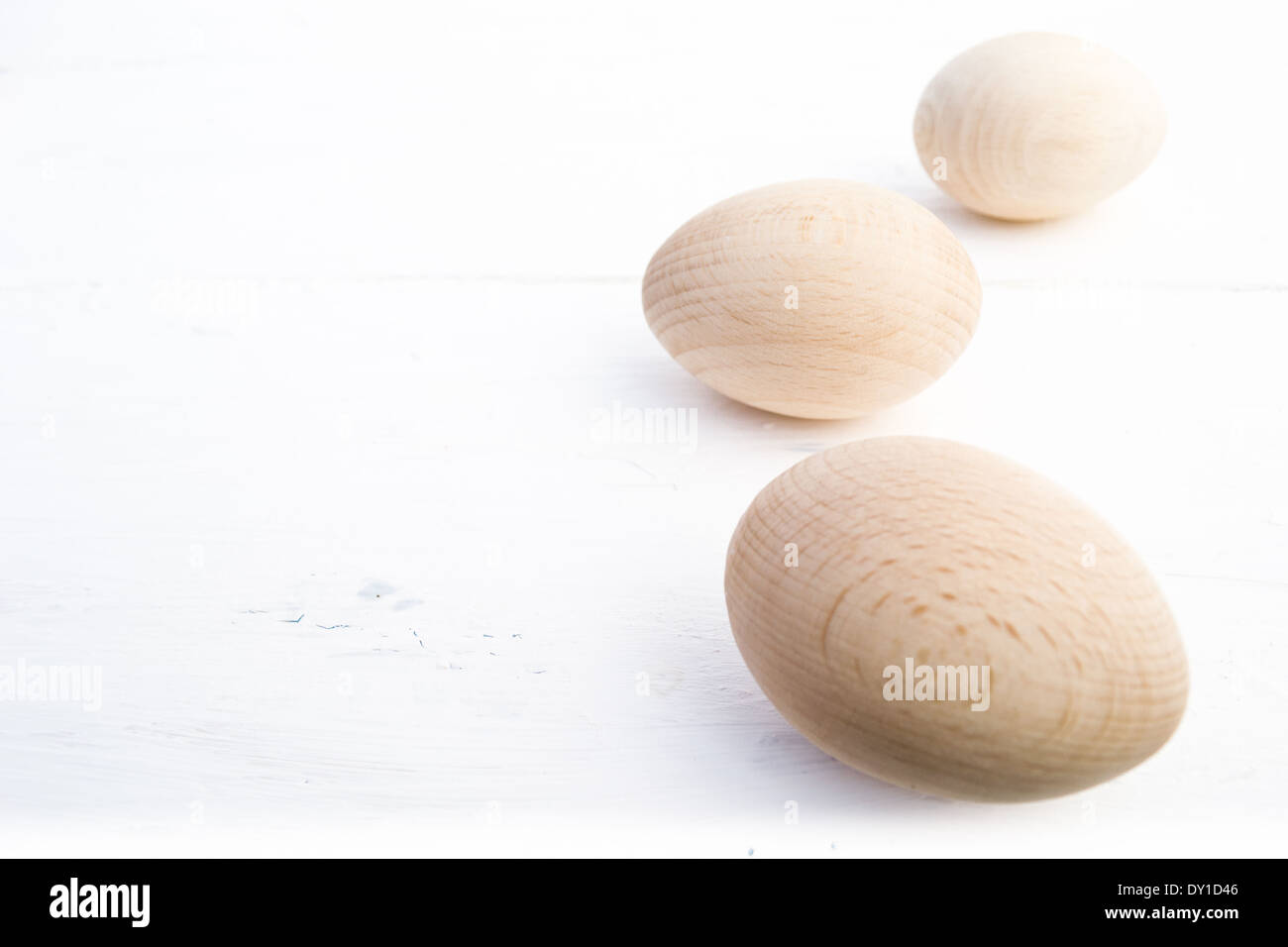 Tre uova di legno disposte dalla parte anteriore a quella posteriore su un lato della foto. Le uova di legno sono in luce naturale e colori. Foto Stock