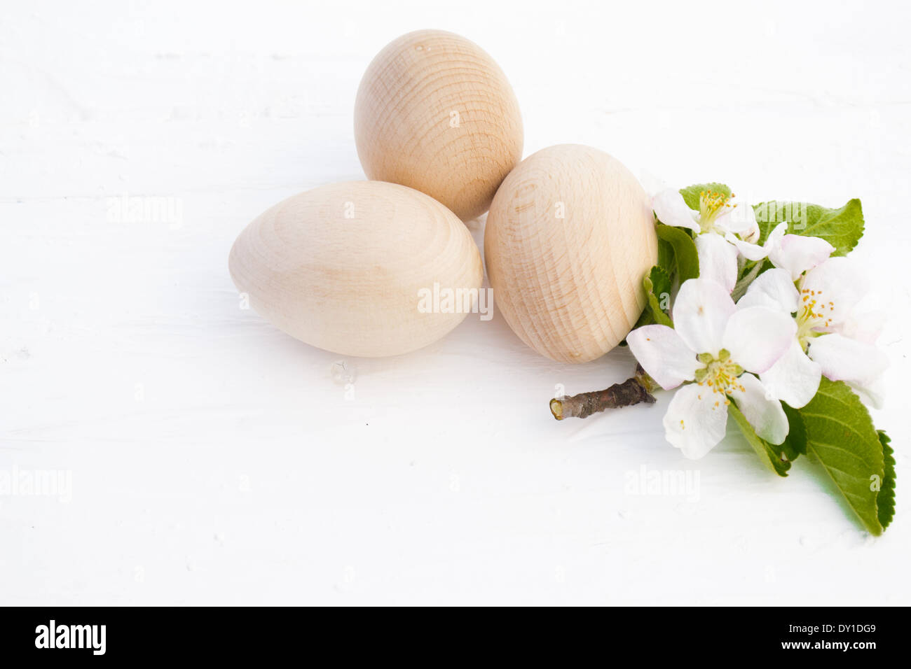 Tre legno/uova di legno e un apple blossom nel centro sul display nella luce naturale. Foto Stock