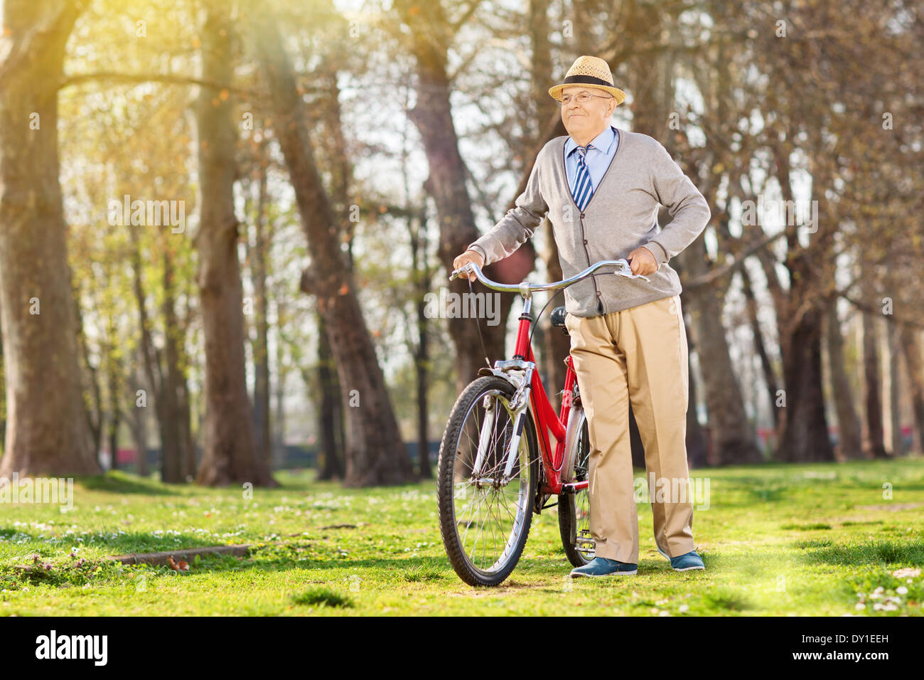 Un anziano spingendo la sua bicicletta in all'aperto Foto Stock