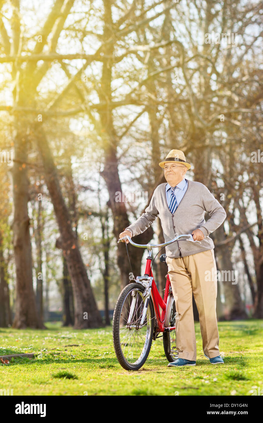 Senior uomo a camminare con la sua bicicletta in posizione di parcheggio Foto Stock