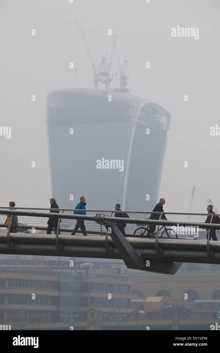 Londra, Regno Unito. 3 Aprile, 2014. London Smog: Millennium Bridge, City of London, Londra, Regno Unito pendolari fanno la loro strada attraverso il Millennium Bridge con il quartiere delle finanze in background avvolta nel smog, mentre il London Smog e polvere rossa travolti dal Sahara continuano a causare elevati livelli di inquinamento atmosferico in tutta la capitale. I punteggi dei voli sono stati annullati e le persone hanno consigliato di rimanere a casa se si soffre di asma o di condizioni del cuore. Credito: Jeff Gilbert/Alamy Live News Foto Stock