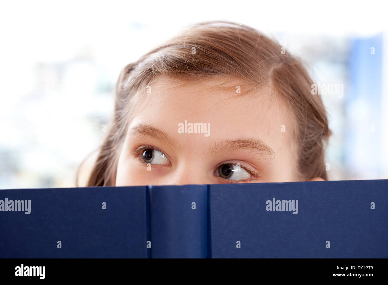 Bambina la lettura di un libro e guardando in alto Foto Stock