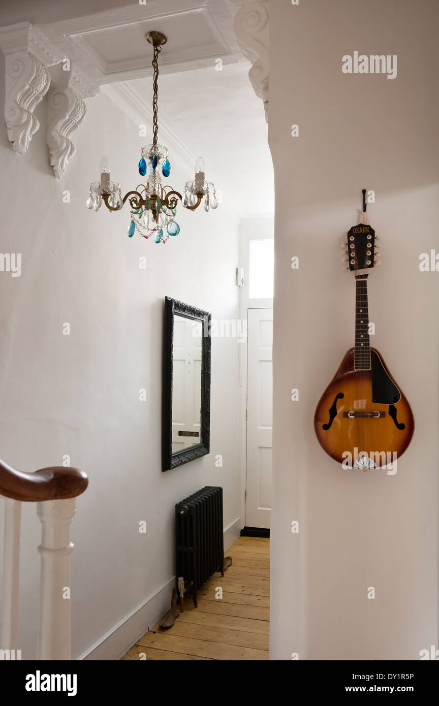 Un mandolino è appeso alla parete di un ingresso con beccatelli e blue drop lampadario Foto Stock