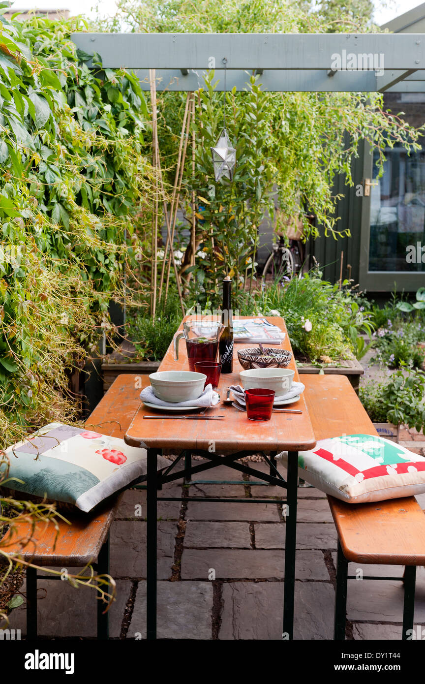 Panca in legno e tavolo su giardino pavimentato patio sotto la pergola in legno con cuscini da Cassandra Ellis Foto Stock