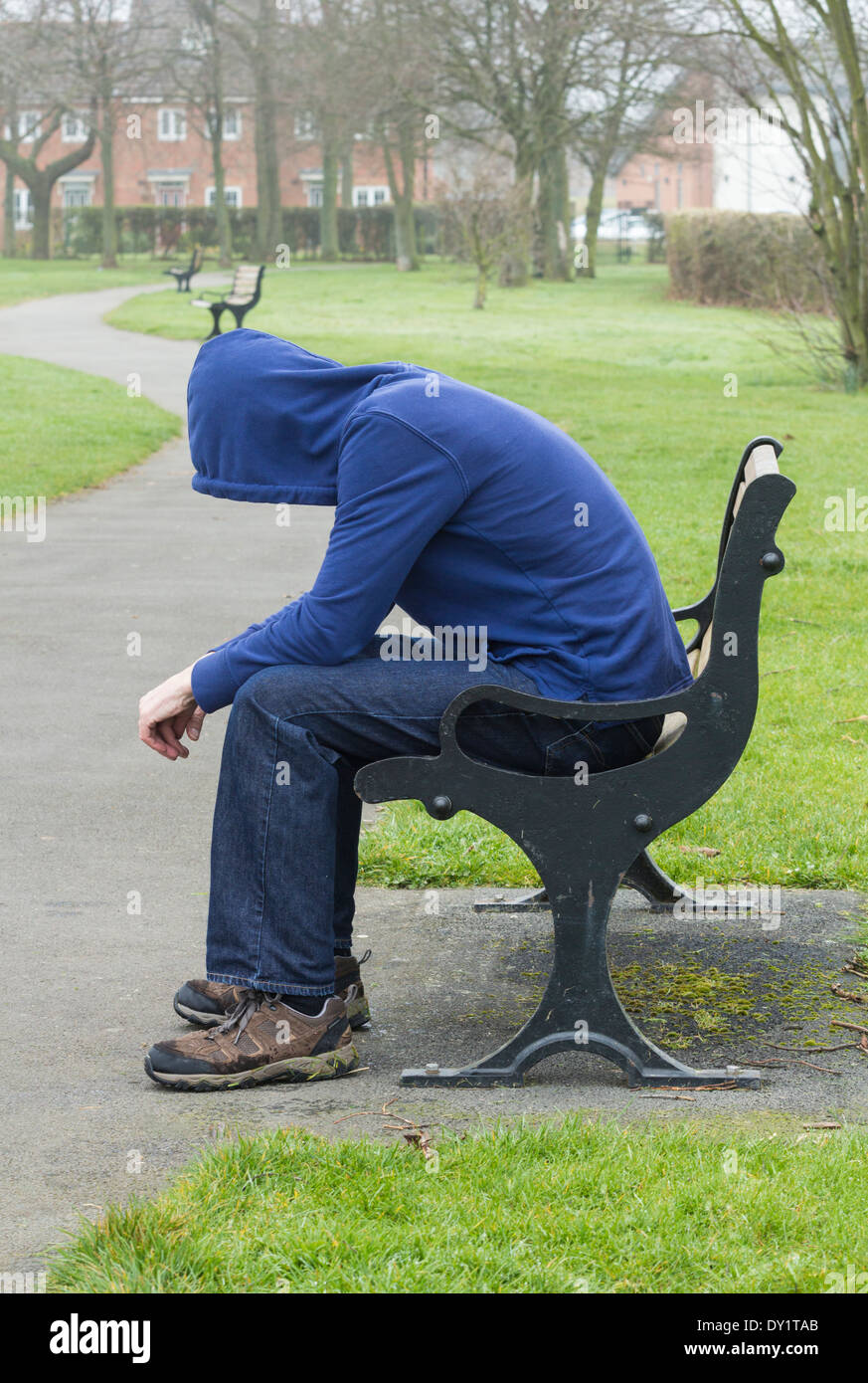 Indossare maschio hoodie seduto su una panchina nel parco Foto Stock