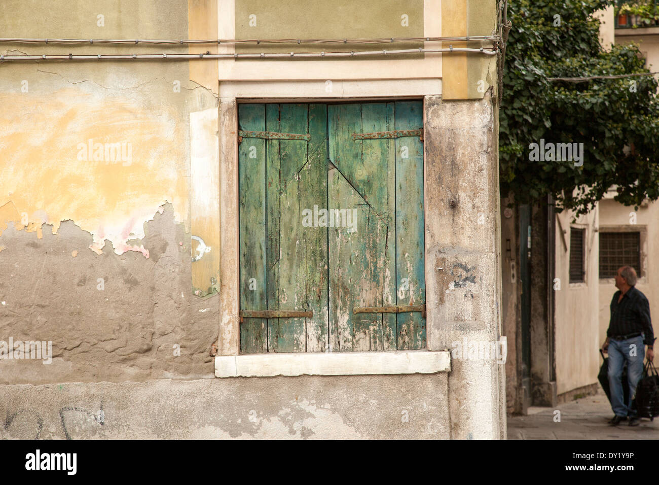 Verde nella finestra ritagliata in giallo, peeling muro di pietra Foto Stock