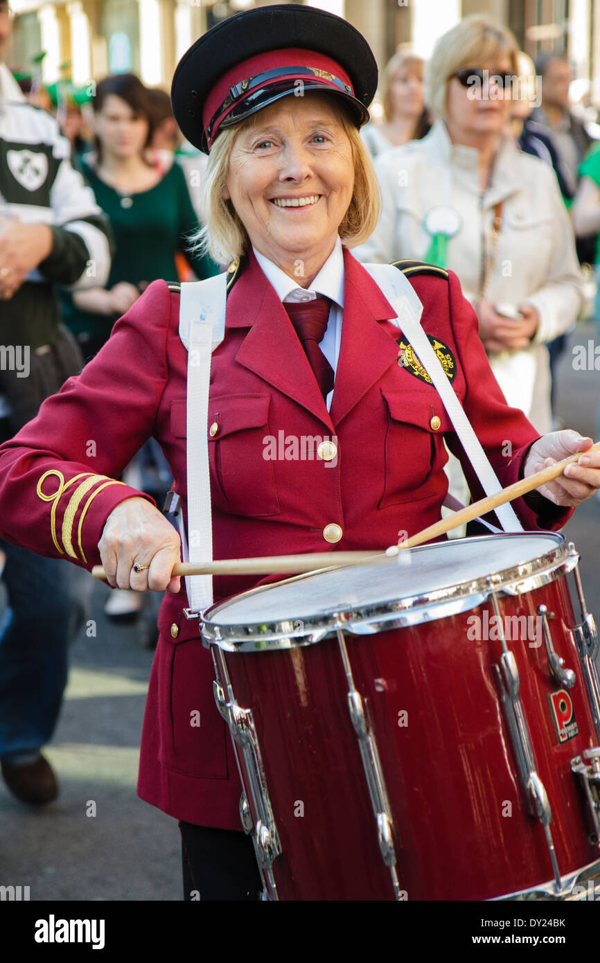 Sorridente, donna matura suonare il tamburo in marching band, London REGNO UNITO Foto Stock
