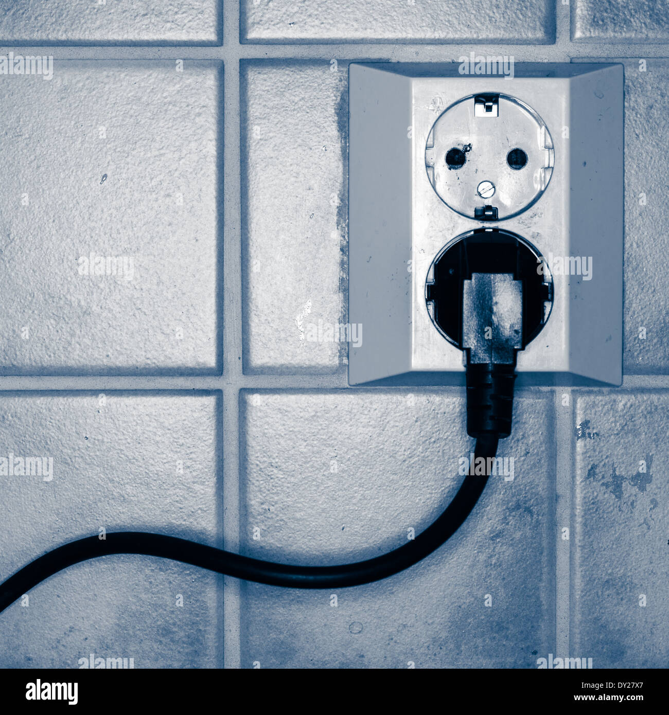 Collegato il cavo di alimentazione nella presa di corrente a muro, oscurata immagine in bianco e nero Foto Stock