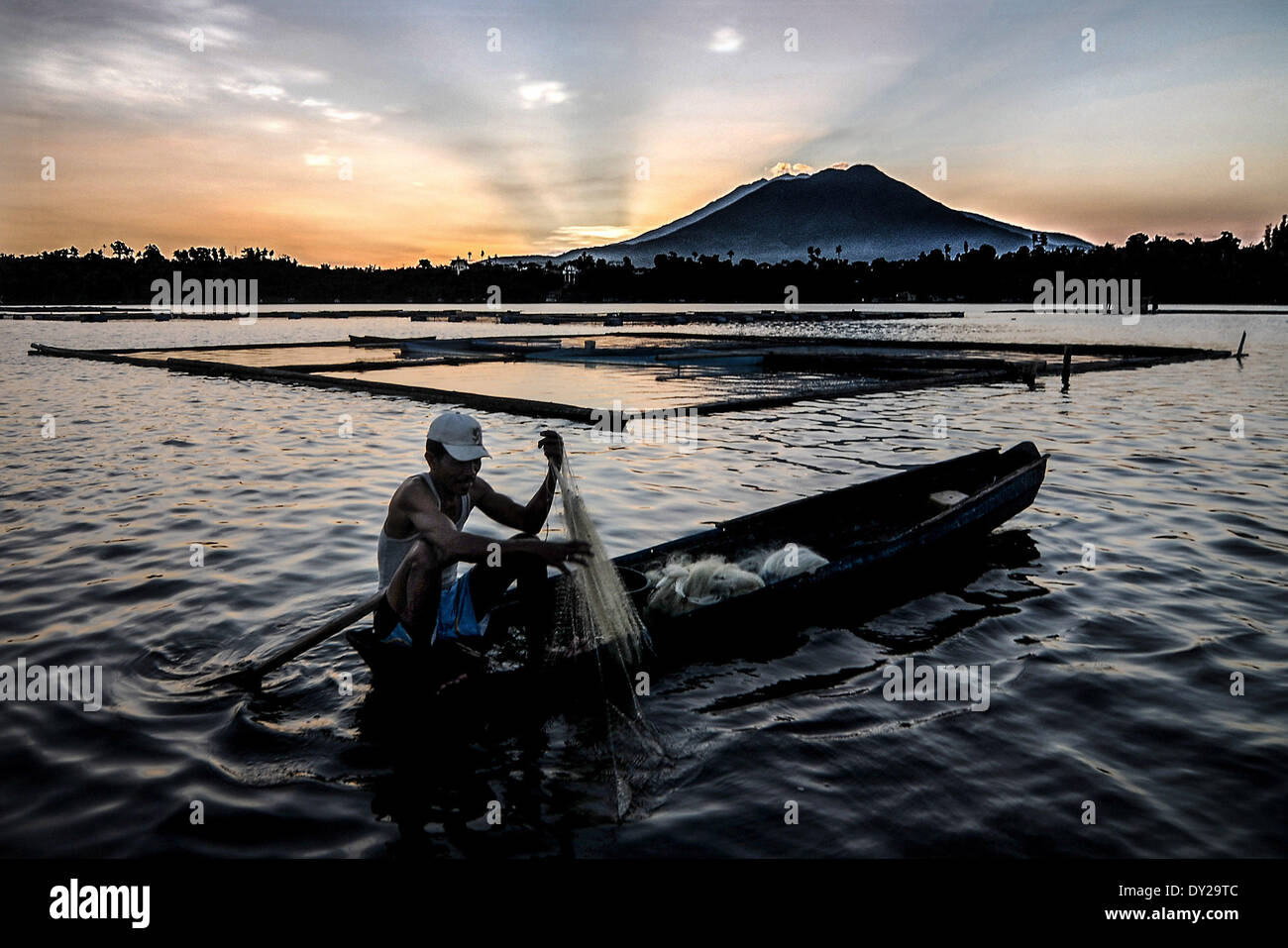 San Pablo, nelle Filippine. 4 apr, 2014. Un pescatore tira la sua cattura come il sole sorge in Sampaloc lago San Pablo città, provincia di Laguna, Filippine, 4 aprile 2014. Le Filippine " sette laghi cratere a San Pablo City, Laguna è stato scelto come il 'minacciato laghi dell'anno 2014Ã¢?Â dalla Germania-ha basato il gruppo ambientale globale del Fondo di natura (GNF). Le occupazioni illegali lungo le rive, sovraffollamento delle penne di pesce e pesce nelle gabbie, e altri illegale costruzione ha colpito i laghi vulcanici negli ultimi decenni.Foto: Ezra Acayan/NurPhoto (credito Immagine: © Ezra Acayan/NurPhoto/ZUMA Foto Stock