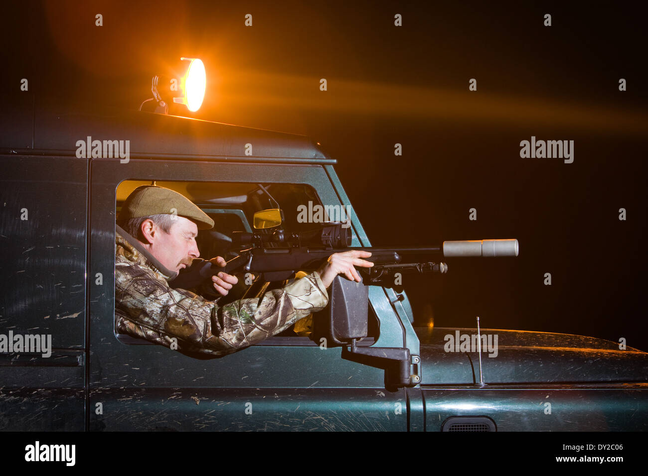 Un gioco Keeper pesti di ripresa di notte da un Land Rover veicolo servendosi di una lampada e un fucile Foto Stock