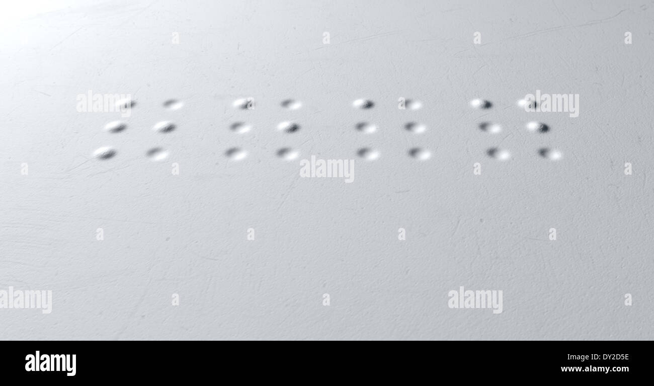 Un concetto di primo piano di una serie di quattro isolati lettere braille ortografia della parola letta su una trama di carta bianca Foto Stock