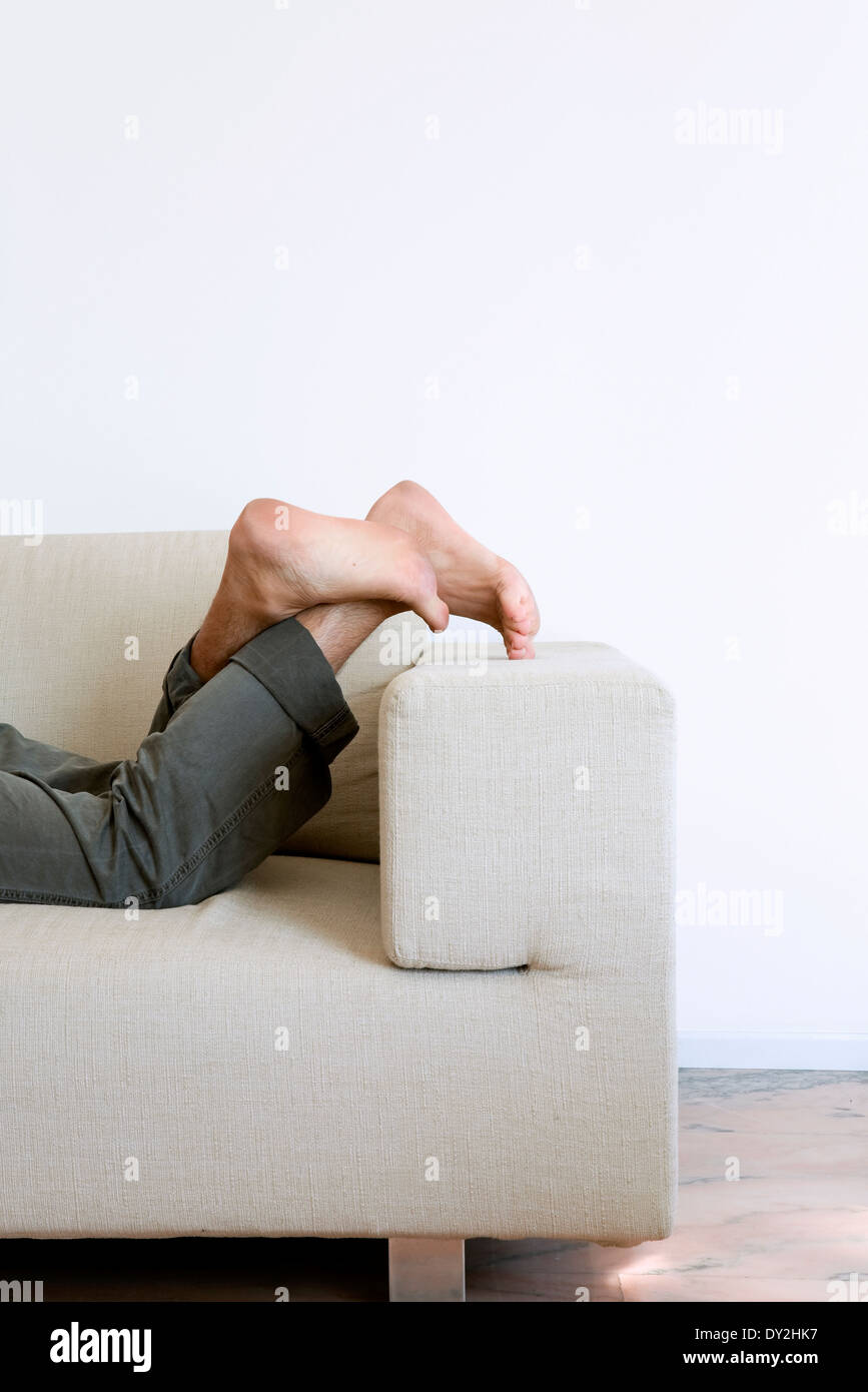 Dettaglio dei piedi dell'uomo sdraiato sul divano Foto stock - Alamy