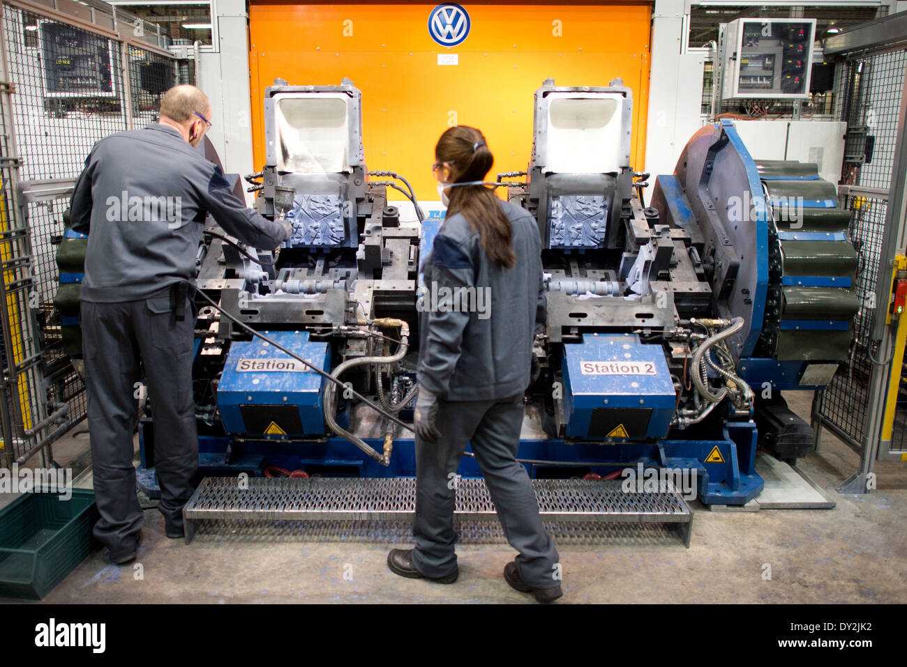 Volkswagen dipendenti stare accanto a una macchina (Doppel-Kippgießmaschine) in fonderia in stabilimento Volkswagen di Hannover, Germania, 04 aprile 2014. In fonderia la maggior parte delle testate sono prodotte. Foto: Julian Stratenschulte/dpa Foto Stock