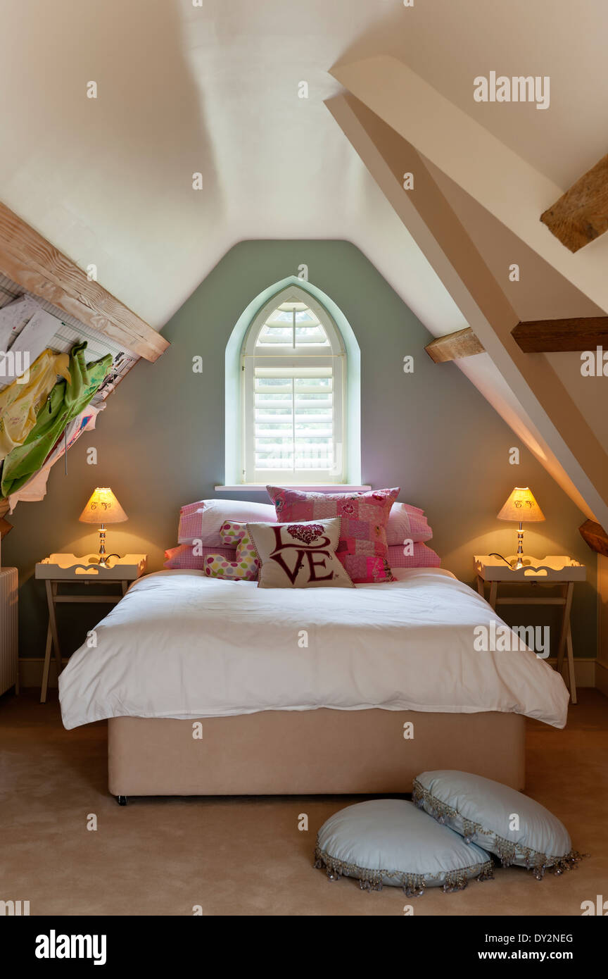 Ragazze mansarda camera da letto con pareti inclinate e la finestra ad arco Foto Stock