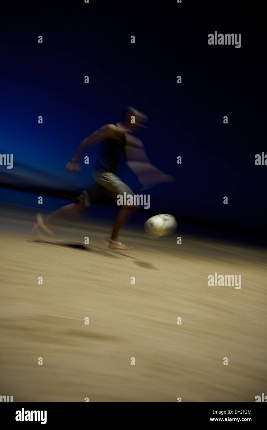 Solo il calcio brasiliano soccer player in esecuzione durante la notte sulla spiaggia in una sfocatura in Nordeste brasile Foto Stock