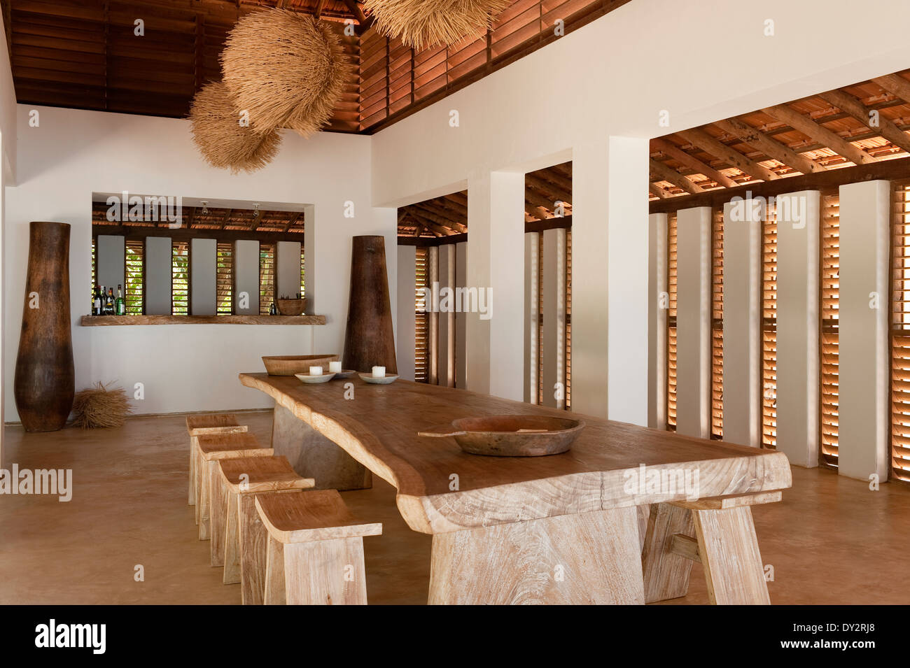 Tavolo da pranzo con sgabelli e grandi urne cinerarie in un piano aperto beach house retreat nello stato indiano di Goa Foto Stock