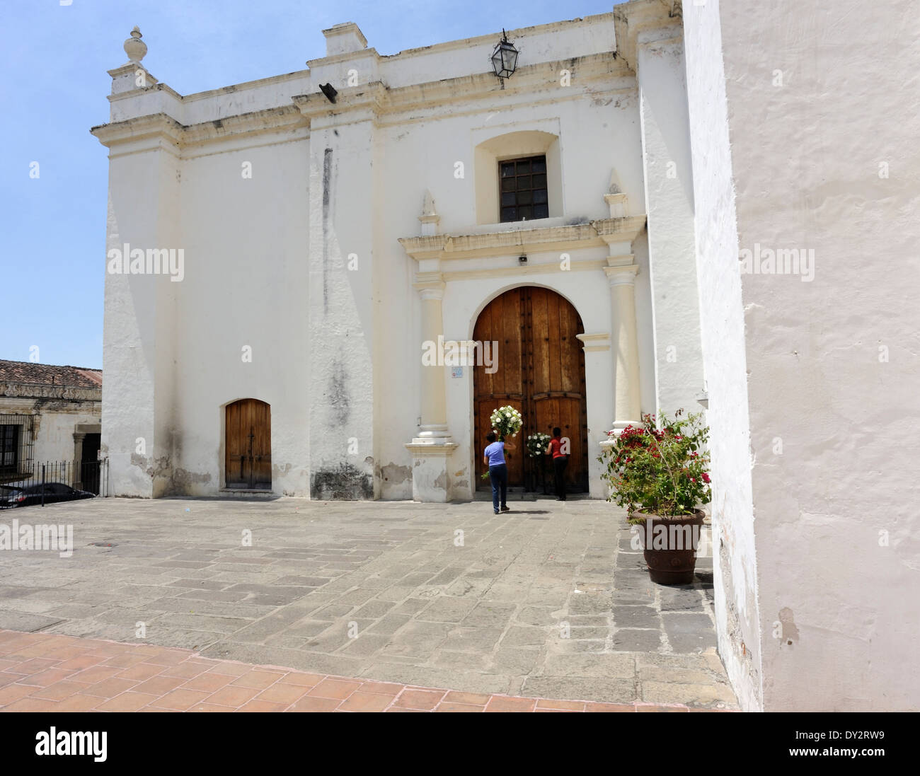 Le donne hanno fiori attraverso una porta laterale per La Catedral. Antigua Guatemala, Repubblica del Guatemala. Foto Stock
