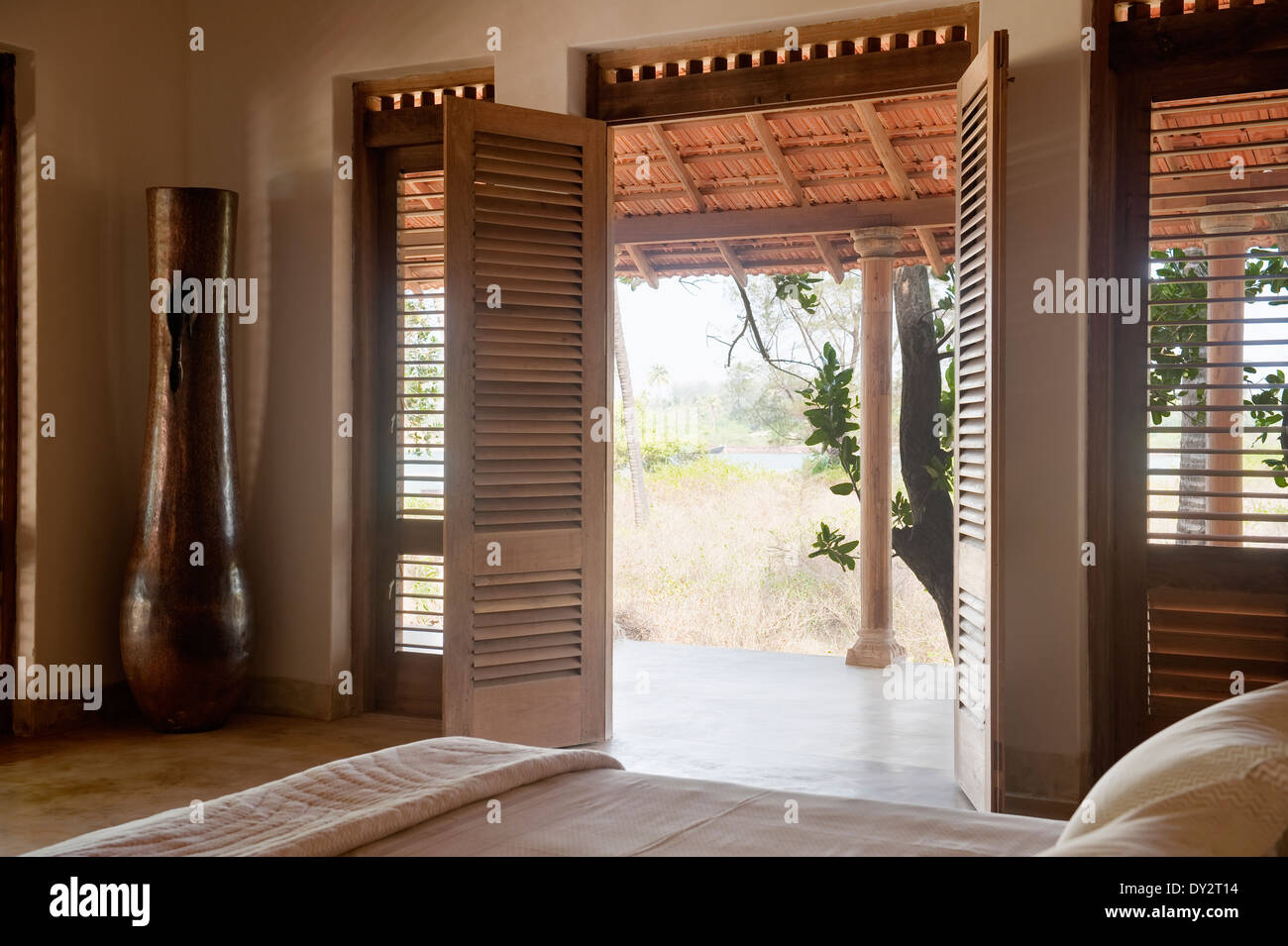 Doppie porte aperte da camera da letto a veranda di Goan beach house retreat, India Foto Stock