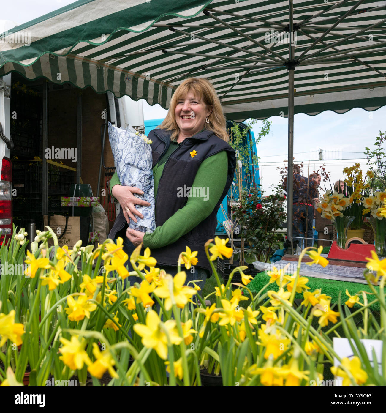 Thriplow, Cambridgeshire, Regno Unito. 5 aprile 2014. Ai visitatori una stallholder vende narcisi come migliaia di persone godono di sole primaverile al Thriplow Daffodil Weekend in Cambridgeshire Regno Unito 5 aprile 2014. Ogni anno tra 7000-10000 persone frequentano il villaggio evento per vedere visualizza dei narcisi, visitando i residenti giardini aperti, craft fienili, chioschi, Morris dancing, paese dimostrazioni di artigianato, pesanti cavalli e fiera del divertimento escursioni. Le strade sono chiuse al traffico consentendo ai visitatori di passeggiare al grazioso villaggio corsie in una celebrazione della primavera. Credito: Julian Eales/Alamy Live News Foto Stock Thriplow, Cambridgeshire, Regno Unito. 5 aprile 2014. Ai visitatori una stallholder vende narcisi come migliaia di persone godono di sole primaverile al Thriplow Daffodil Weekend in Cambridgeshire Regno Unito 5 aprile 2014. Ogni anno tra 7000-10000 persone frequentano il villaggio evento per vedere visualizza dei narcisi, visitando i residenti giardini aperti, craft fienili, chioschi, Morris dancing, paese dimostrazioni di artigianato, pesanti cavalli e fiera del divertimento escursioni. Le strade sono chiuse al traffico consentendo ai visitatori di passeggiare al grazioso villaggio corsie in una celebrazione della primavera. Credito: Julian Eales/Alamy Live News Foto Stock
