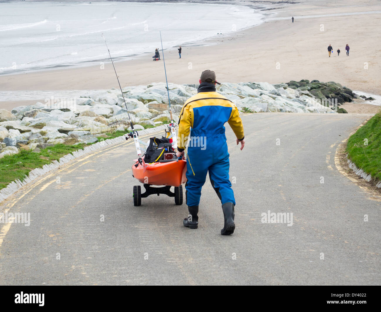 Uomo con un ben attrezzato Kayak tenendo giù al mare per un viaggio di pesca a Nord Yorkshire coast Foto Stock