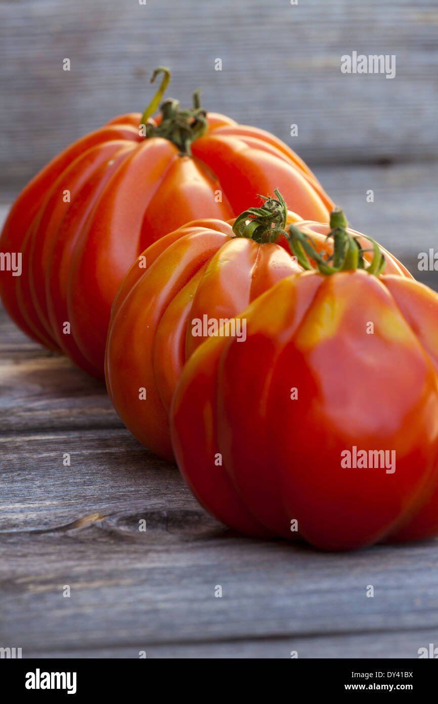 Tre grandi bistecca di manzo pomodori in una fila fresco dal mercato settimanale su un vecchio tavolo in legno Foto Stock