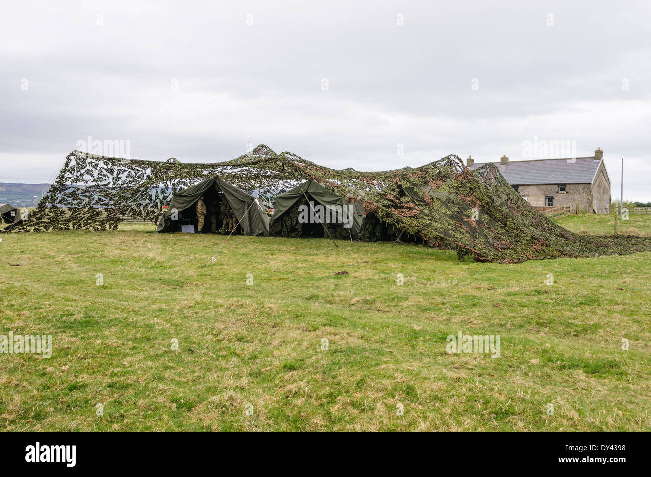 Tende appartenenti ad un mobile posto di comando sono coperti con camouflage netting in un campo Foto Stock
