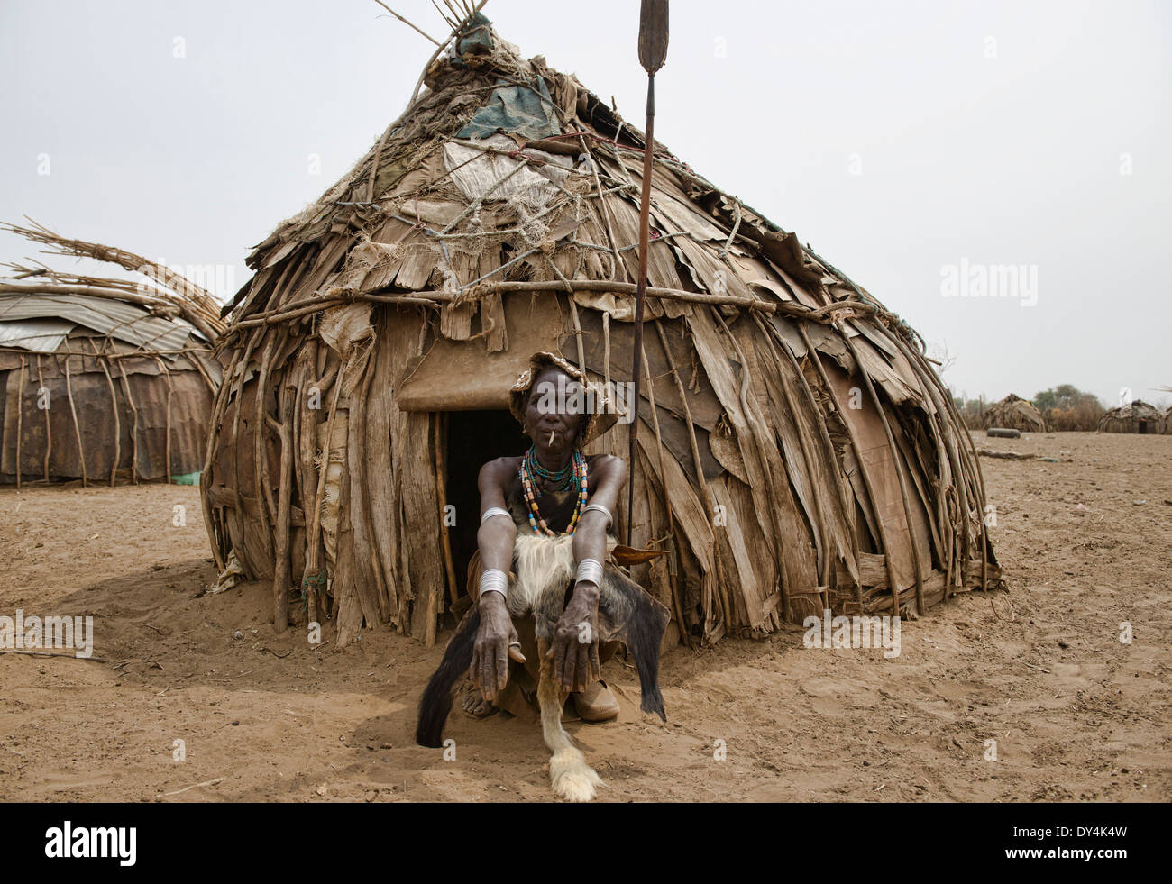 Vecchia donna Dassanech nella parte anteriore del suo rifugio nella bassa valle dell'Omo di Etiopia Foto Stock