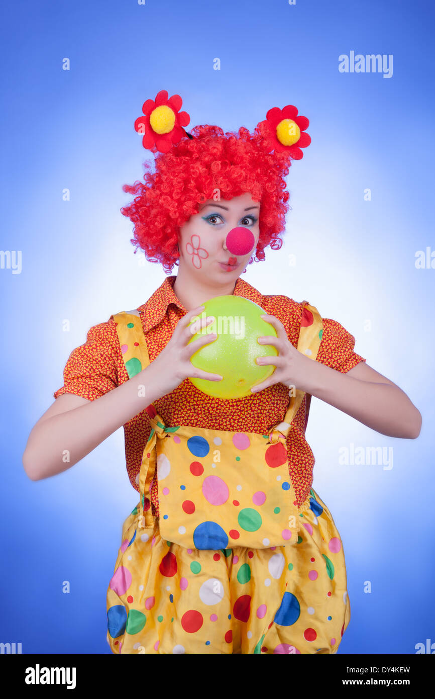 Clown donna con una sfera su sfondo blu. Riprese in studio Foto Stock