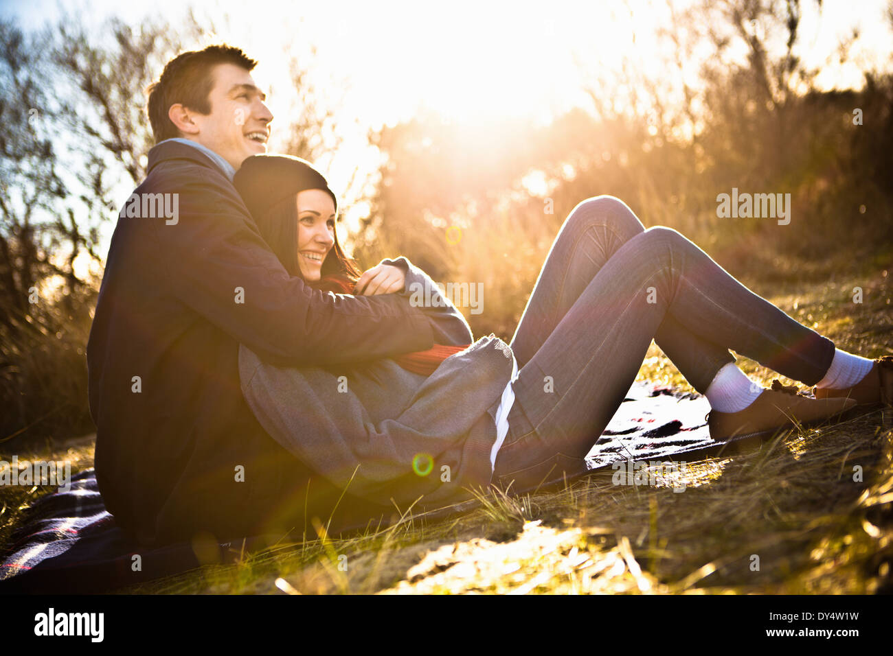 Giovane seduto sulla coperta picnic avvolgente Foto Stock