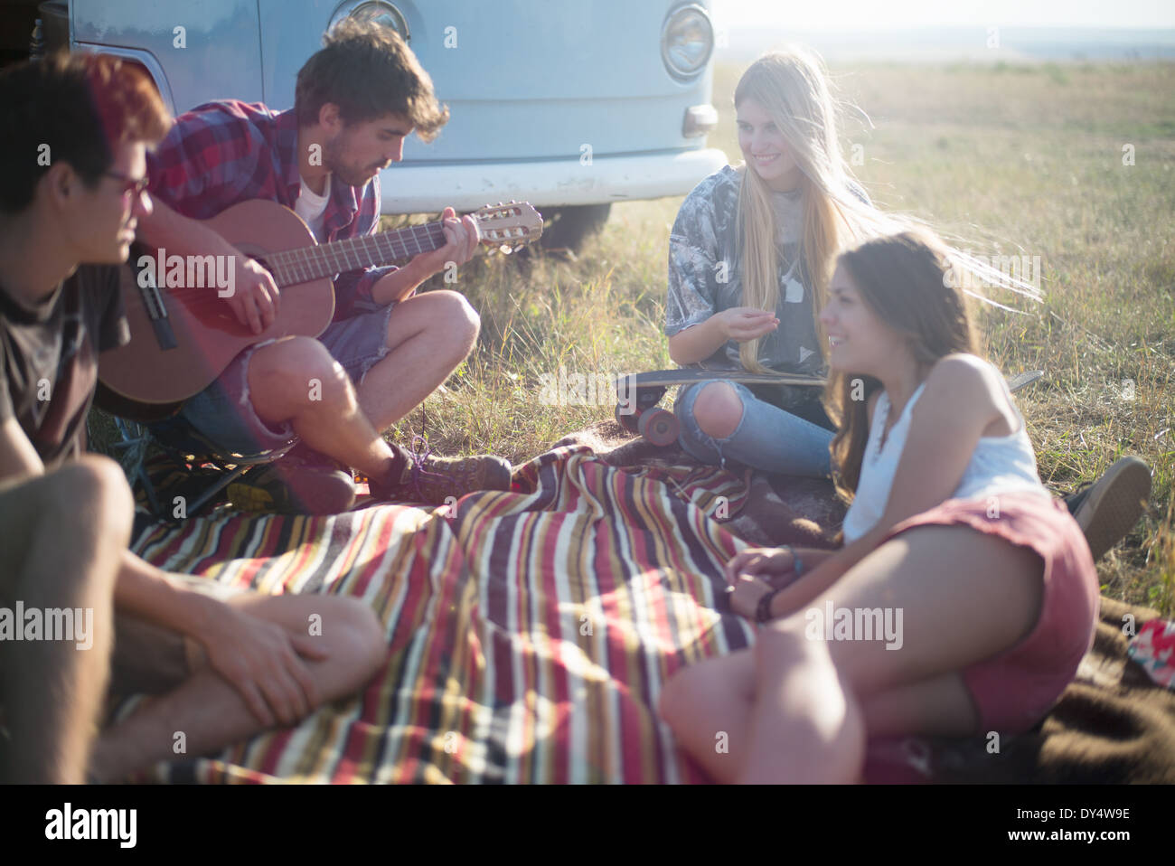 Amici sulla coperta picnic con uomo a suonare la chitarra Foto Stock