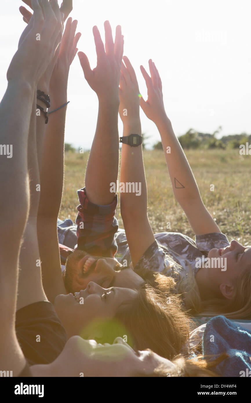 Quattro amici che giace sul dorso con le braccia sollevate Foto Stock