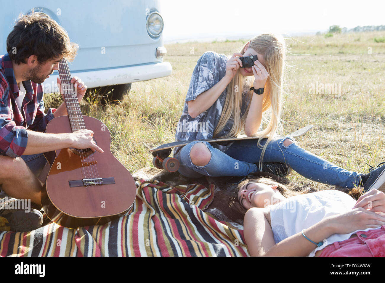 Giovane uomo suonare la chitarra, giovani donne in ascolto Foto Stock