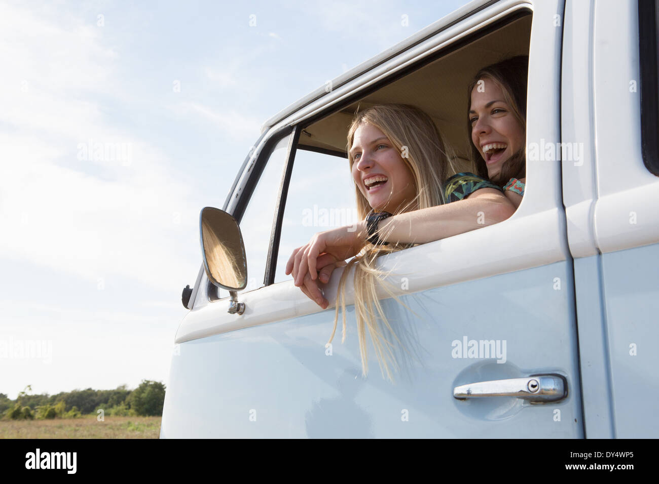 Giovani donne guardando fuori della finestra caravan ridere Foto Stock
