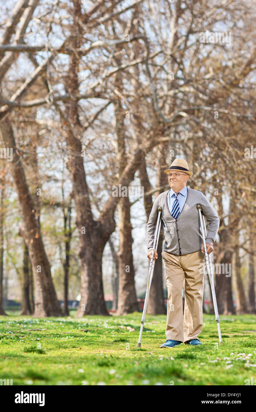 Anziano gentiluomo camminare con le stampelle in posizione di parcheggio Foto Stock