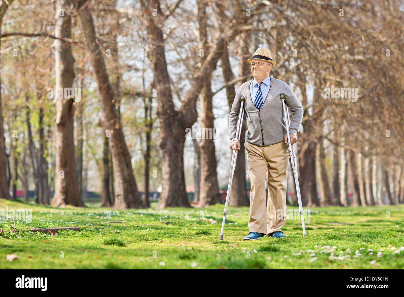 Senior gentleman camminando con le stampelle in posizione di parcheggio Foto Stock