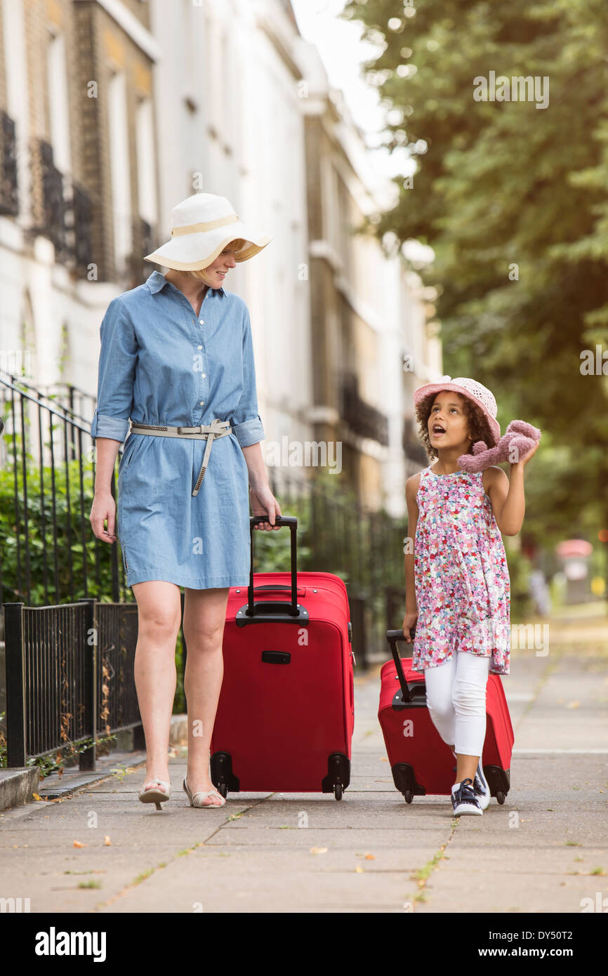 Madre e figlia tirando le valigie lungo il marciapiede Foto Stock