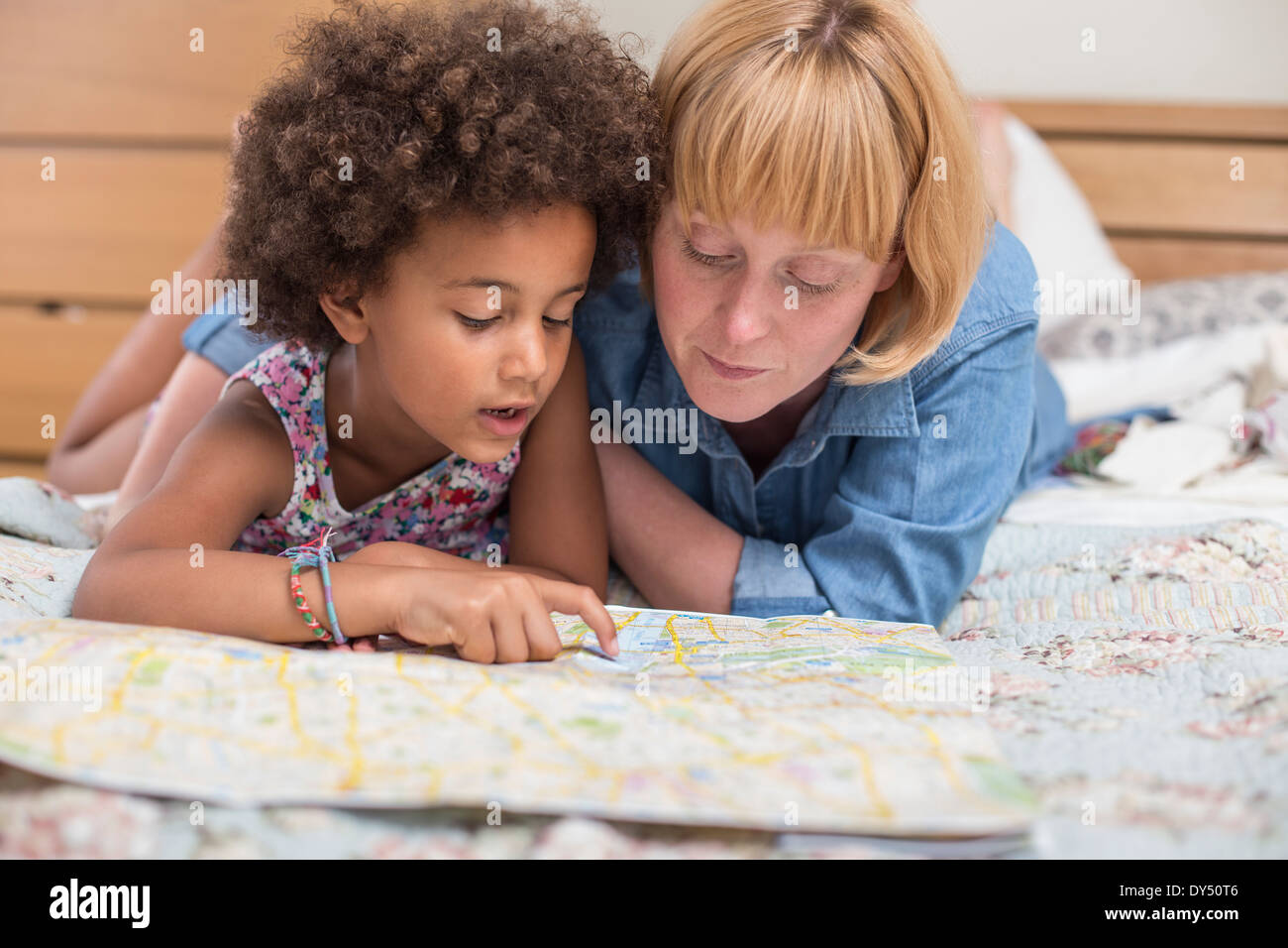 Madre e figlia giacente sul letto, guardando alla mappa Foto Stock