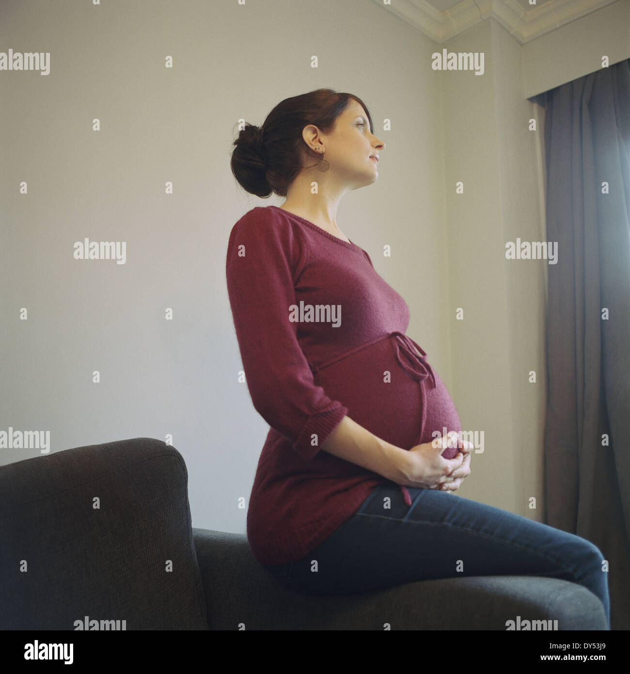 Donna incinta che guarda lontano Foto Stock