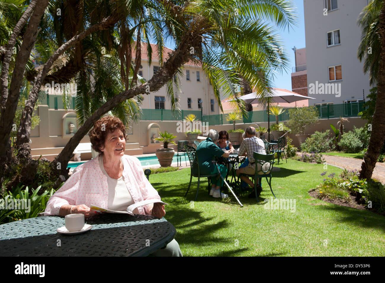 Senior donna avente il caffè nel giardino della villa di pensionamento Foto Stock